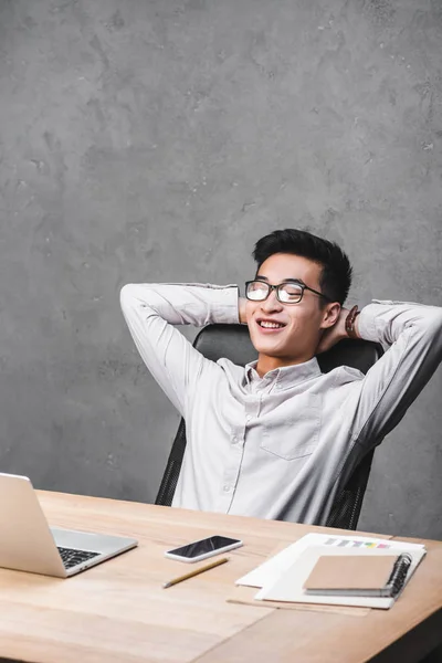 Smiling asian seo manager sitting at table with crossed arms — Stock Photo