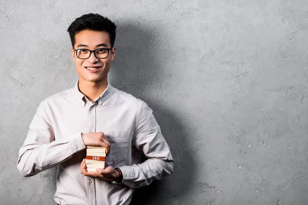 Sorridente asiatico seo manager holding legno rettangoli con lettering seo — Foto stock