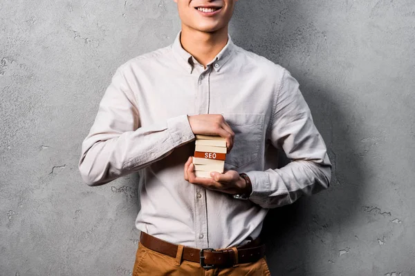 Vista ritagliata di sorridente seo manager in possesso di rettangoli in legno con scritte seo — Foto stock