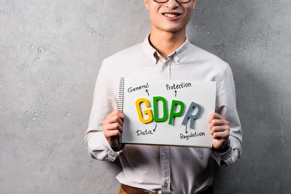 Recortado vista de sonriente empresario sosteniendo papel con letras gdpr - foto de stock