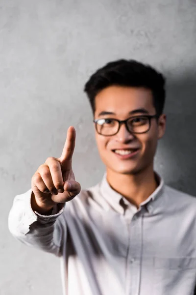 Selective focus of smiling asian seo manager pointing with finger — Stock Photo