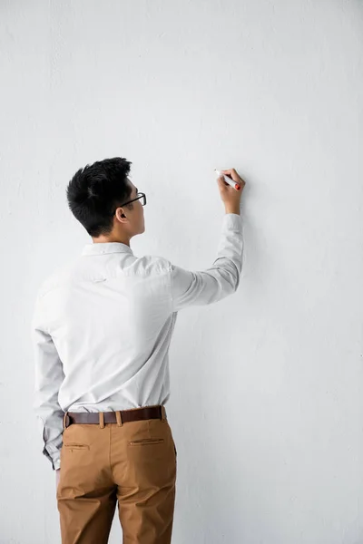 Back view of seo manager writing on white wall — Stock Photo