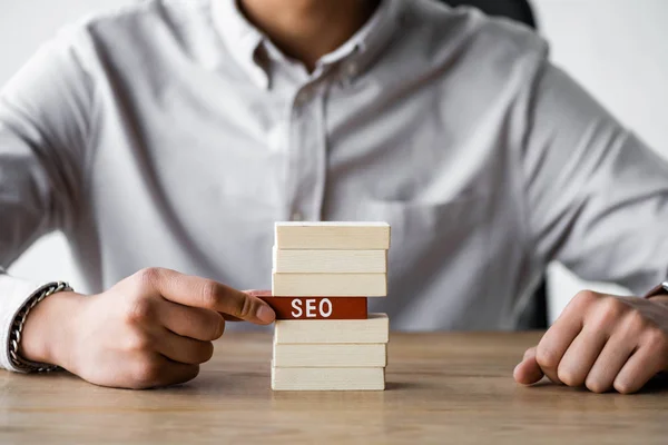 Vista recortada de seo manager celebración de rectángulo de madera con letras seo - foto de stock