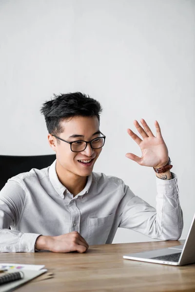 Sorrindo asiático seo gerente acenando durante webinar no escritório — Fotografia de Stock