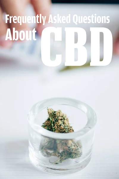 Selective focus of medical marijuana buds in glass bottle with frequently asked questions about cbd illustration — Stock Photo