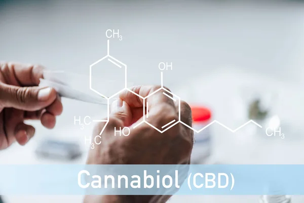 Vista recortada del hombre sosteniendo romo de cannabis medicinal con ilustración de molécula de cbd - foto de stock