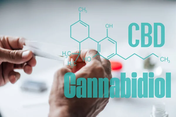 Cropped view of man holding blunt of medical cannabis with cbd molecule illustration — Stock Photo