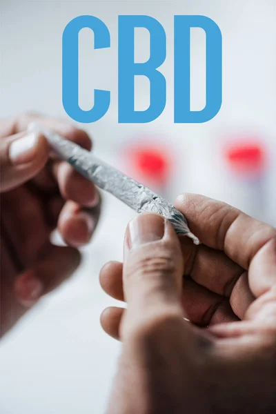 Vista recortada del hombre sosteniendo romo de cannabis medicinal con palabra CBD - foto de stock