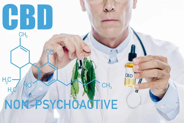 Cropped view of doctor in white coat holding cbd oil and marijuana leaf isolated on white with non-psychoactive cbd illustration — Stock Photo
