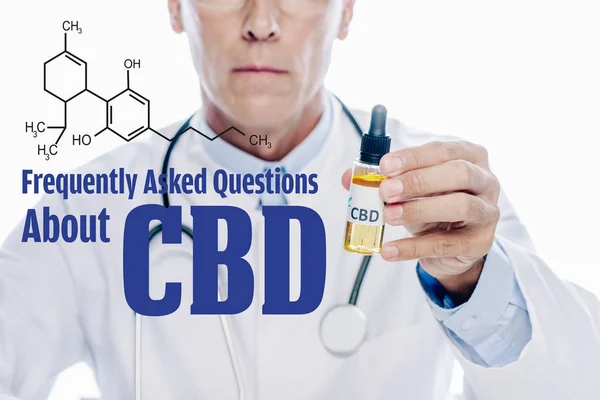 Cropped view of doctor in white coat holding cbd oil isolated on white with frequently asked questions about cbd illustration — Stock Photo