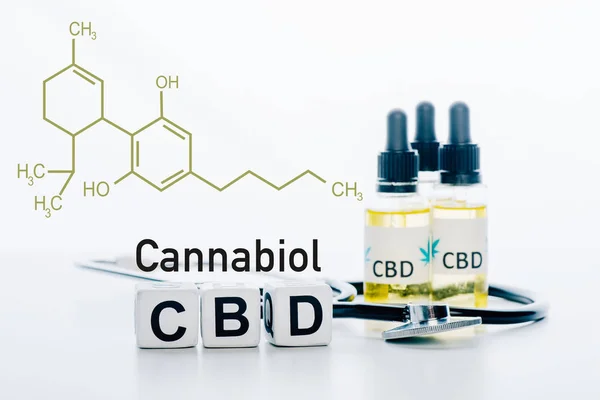 Würfel mit cbd Schriftzug in der Nähe von Öl und Stethoskop isoliert auf weiß mit cbd Molekül Illustration — Stockfoto