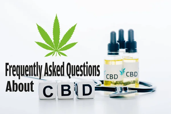 Кубы с надписью cbd рядом с маслом и стетоскопом изолированы на белом с часто задаваемыми вопросами об иллюстрации cbd — стоковое фото