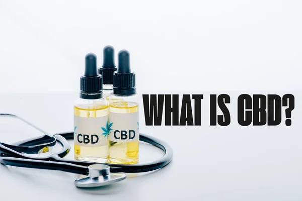 Cbd oil in bottles and stethoscope isolated on white with what is CBD question — Stock Photo