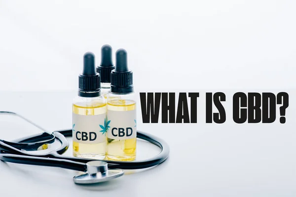 Cbd масло в бутылках и стетоскоп изолированы на белом с чем вопрос CBD — стоковое фото