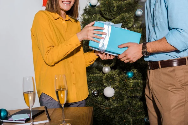 Cropped view of man giving present to woman near christmas tree — Stock Photo