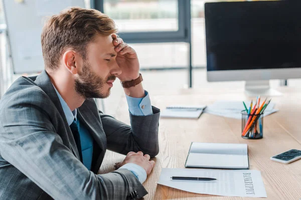 Tired man sitting with headache in office near bankruptcy form — Stock Photo