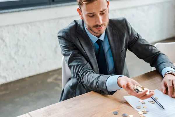 Triste hombre de negocios lanzando monedas cerca de papel con cartas de quiebra - foto de stock