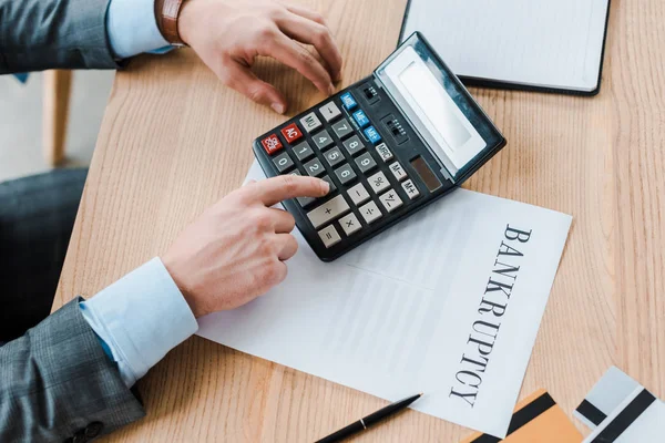 Top view of man using calculator near paper with banknote letters — Stock Photo