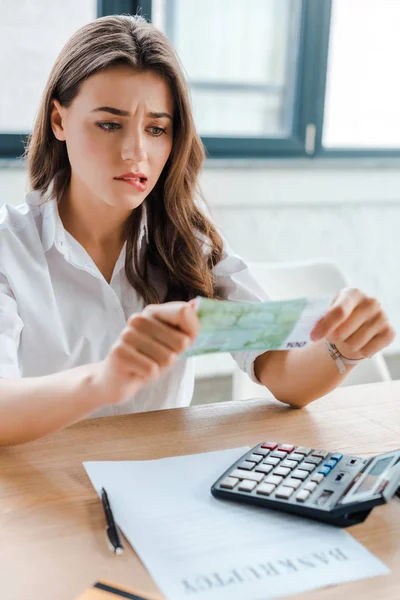 Enfoque selectivo de mujer atractiva mirando el billete en euros mientras muerde los labios — Stock Photo