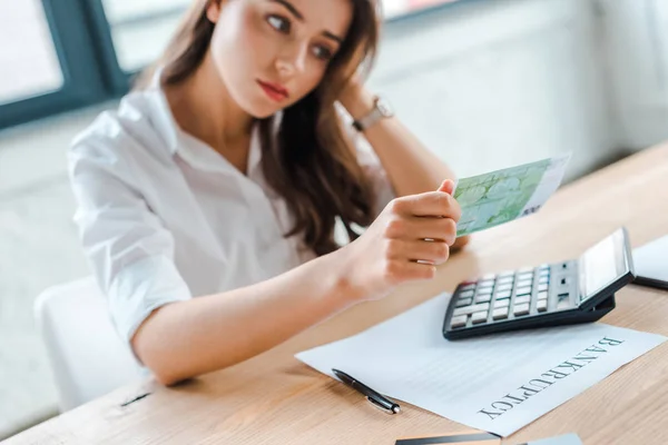 Traurige Frau blickt im Amt auf Euro-Banknote — Stockfoto