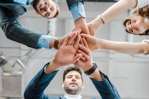 Visão inferior de empresários e empresárias dando as mãos juntos — Fotografia de Stock
