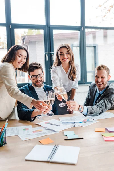 Вибірковий фокус щасливих мультикультурних бізнесменів і бізнесменів, що тримають келихи шампанського в офісі — стокове фото