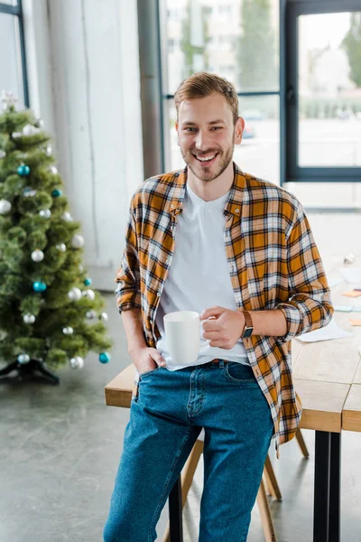 Selektiver Fokus des glücklichen Mannes, der Tasse in der Nähe des geschmückten Weihnachtsbaums hält — Stockfoto