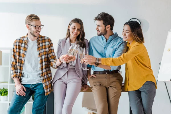 Alegres hombres de negocios y mujeres de negocios multiculturales brindar copas de champán en la oficina - foto de stock