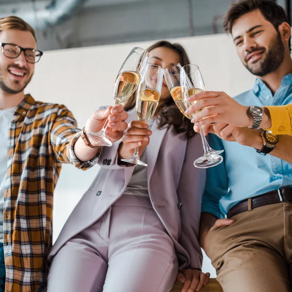 Foco seletivo de empresários alegres e mulheres de negócios torrando copos de champanhe no escritório — Fotografia de Stock