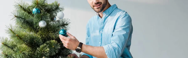 Panoramaaufnahme eines glücklichen bärtigen Mannes, der den Weihnachtsbaum im Büro schmückt — Stockfoto