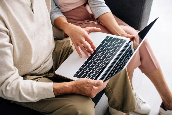 Vista ritagliata di marito e moglie utilizzando il computer portatile in appartamento — Foto stock