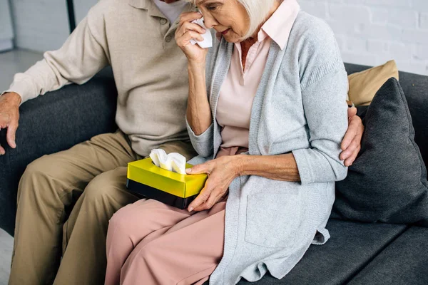 Cropped view of husband and wife crying and holding napkin in apartment — Stock Photo