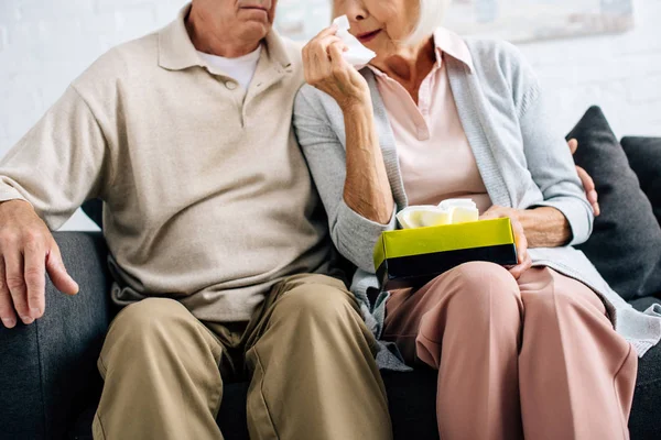 Cropped view of husband and wife crying and holding napkin in apartment — Stock Photo