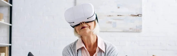 Colpo panoramico di donna anziana con auricolare realtà virtuale in appartamento — Foto stock