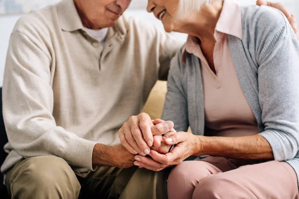 Cropped view of husband and wife holding hands in apartment — Stock Photo