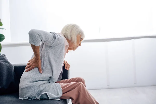 Side view of senior woman having back pain in apartment — Stock Photo