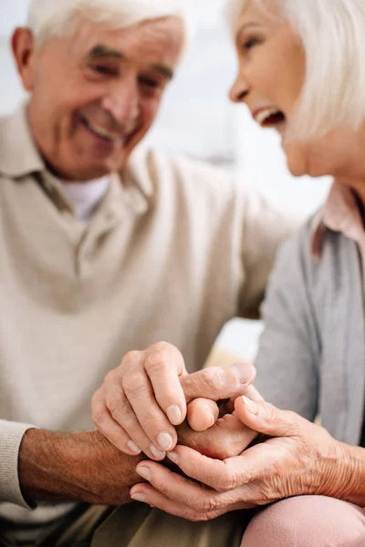 Selective focus of smiling husband and wife holding hands in apartment — Stock Photo