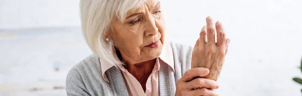 Panoramic shot of senior woman having Arthritis in hand in apartment — Stock Photo