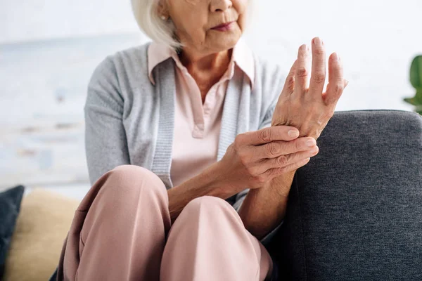 Vista ritagliata della donna anziana che ha l'artrite in mano in appartamento — Foto stock