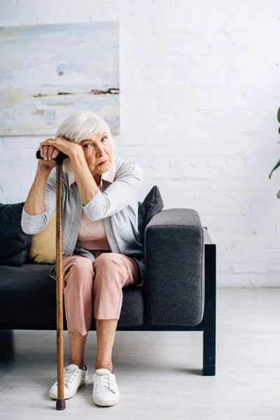 Seniorin mit Holzstock blickt in Wohnung in Kamera — Stockfoto