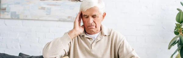 Panoramic shot of senior man having headache in apartment — Stock Photo