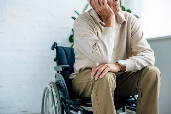 Cropped view of senior man sitting in wheelchair in apartment — Stock Photo