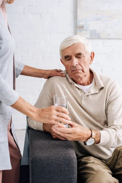 Abgeschnittene Ansicht der Frau, die ihrem Mann ein Glas Wasser gibt — Stockfoto