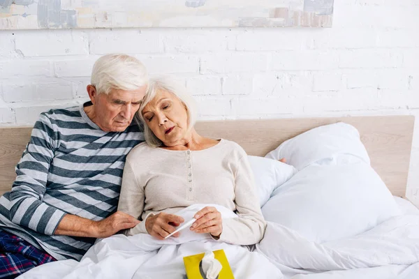 Bello marito e moglie guardando termometro in appartamento — Foto stock