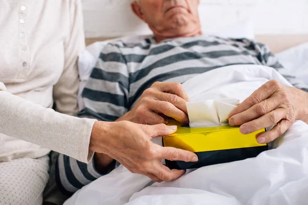 Cropped view of wife giving napkins to ill husband in apartment — Stock Photo