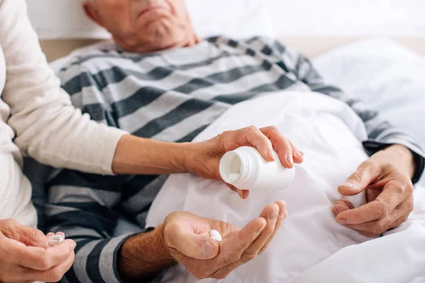 Cropped view of wife giving pills to ill husband — Stock Photo