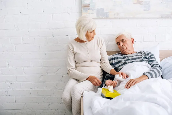 Seniorin gibt kranken Mann Tabletten im Bett — Stockfoto