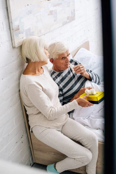 High angle view of husband using nasal drops and wife holding napkins in apartment — Stock Photo