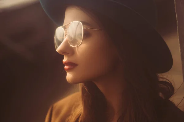 Beautiful retro girl posing in eyeglasses and hat on urban roof — Stock Photo