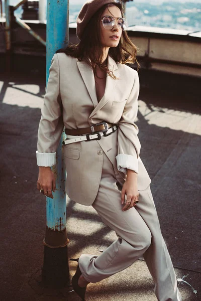 Belle fille à la mode posant en costume beige et béret sur le toit — Photo de stock